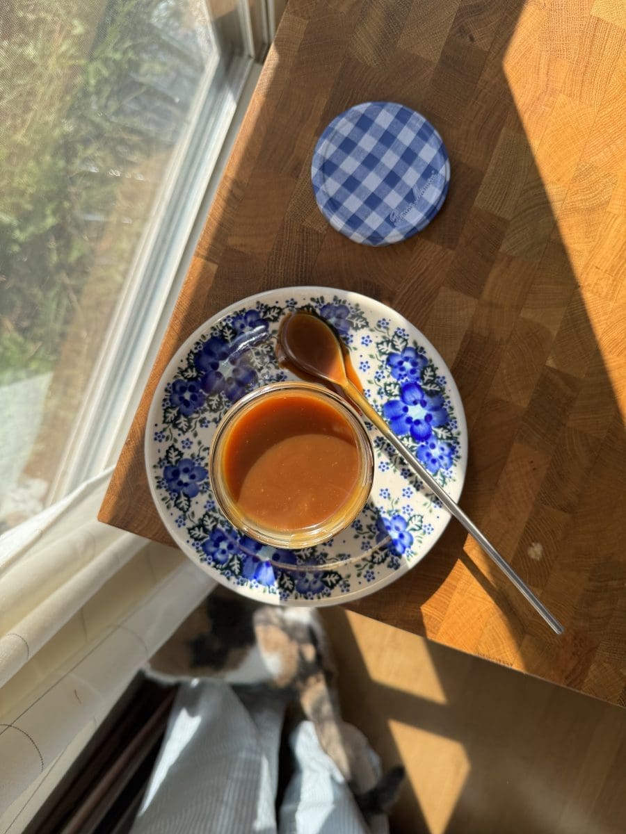 The homemade salted caramel place open in a jar on a decorative plate.