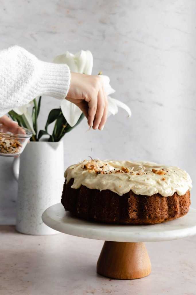 still of sprinkling toasted coconut and walnuts on top of the cake