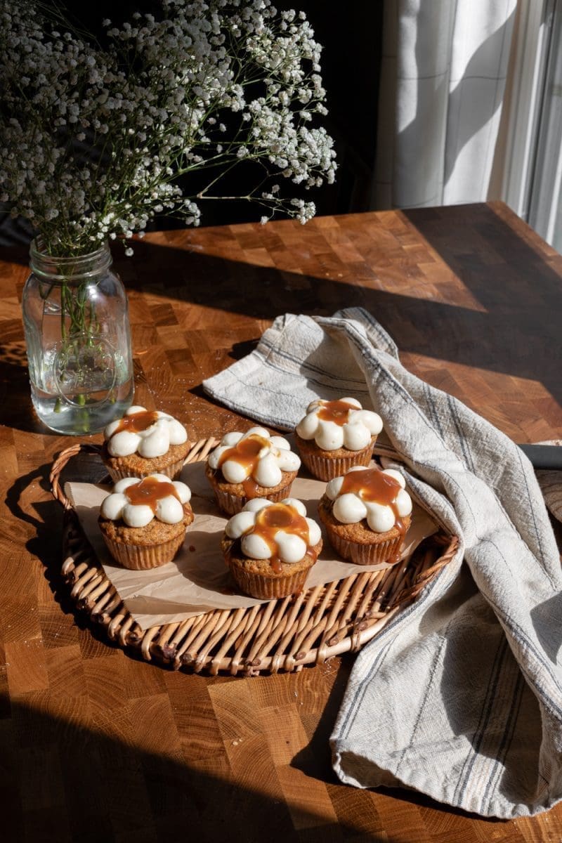 Small batch carrot cakes on a tray next to some flowers.