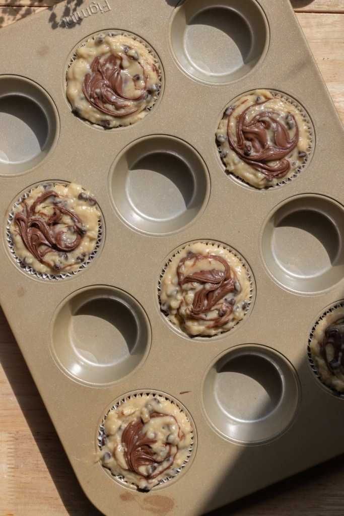 The small batch banana nutella muffin batter distributed between six parchment liners in a muffin tin.