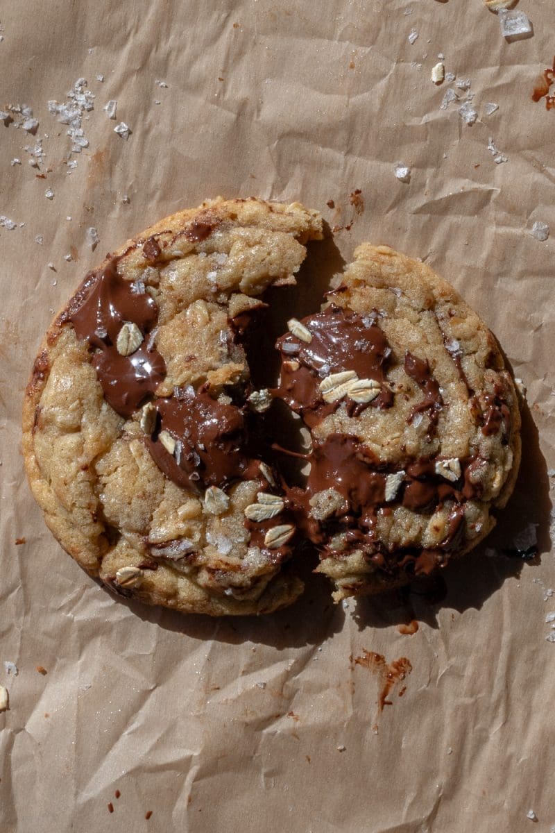 A brown butter oatmeal chocolate chip cookie that has been broken in half.
