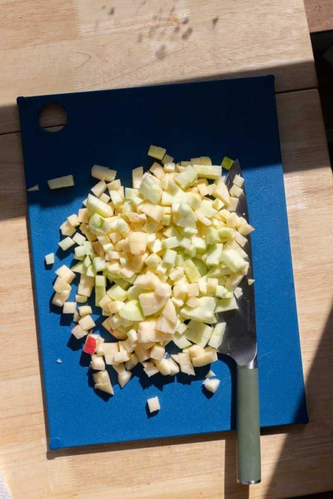 The apples all diced up on a cutting board.