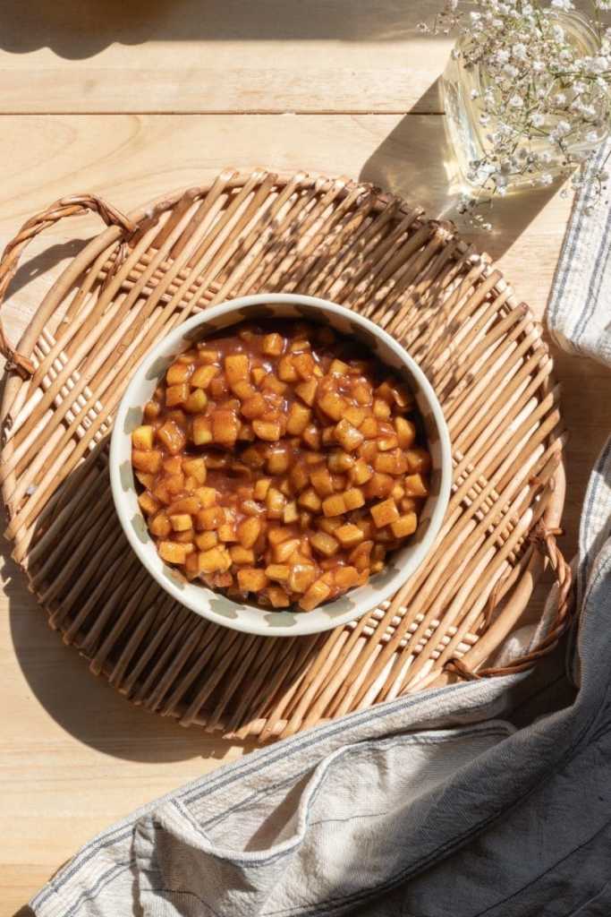 The apple pie filling in a bowl on a serving tray.