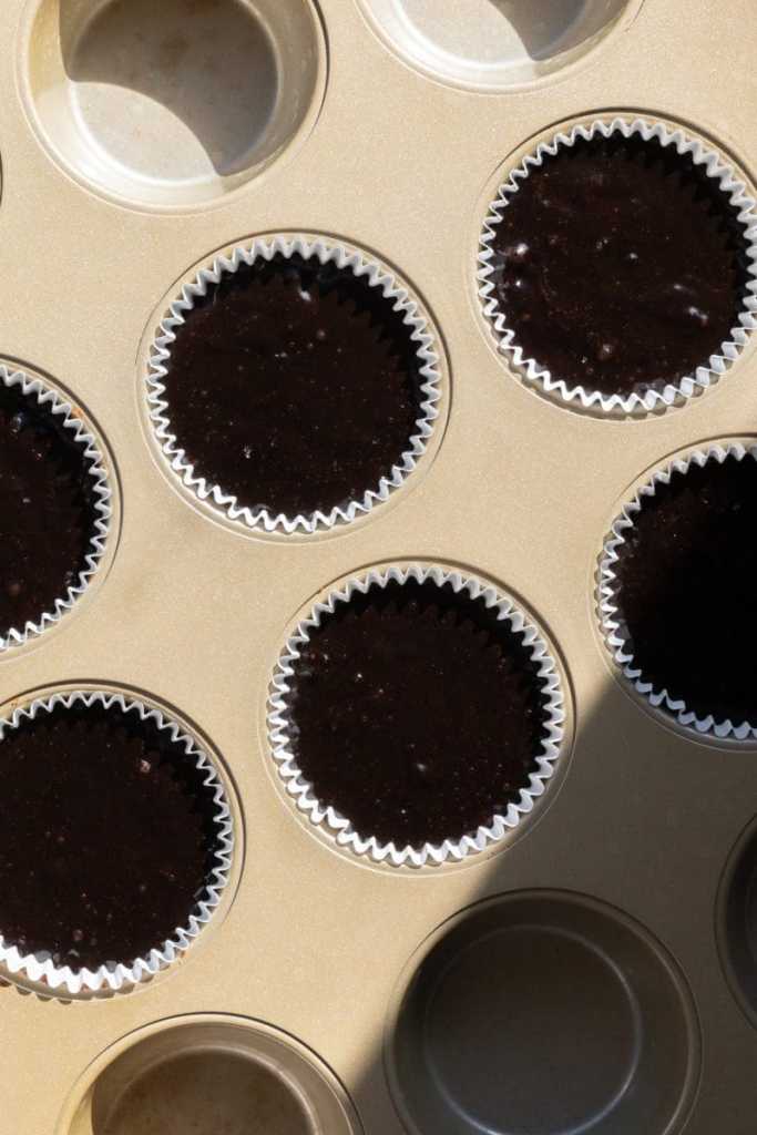 The cupcake batter distributed between cupcake liners.