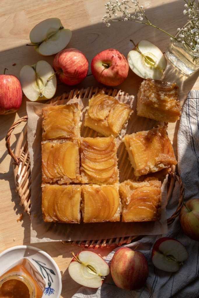 Overview of the sliced caramel apple upside down cake on a serving tray, surrounded by apples.