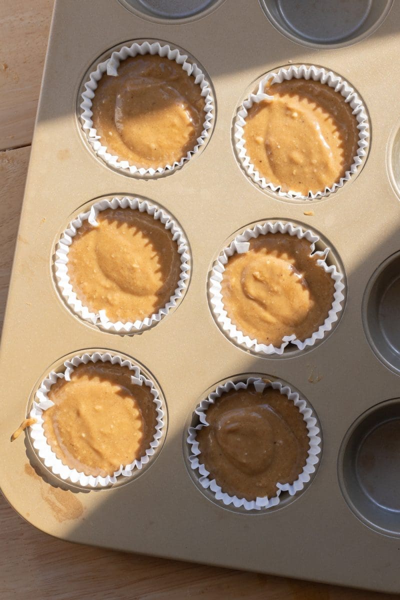 The cupcake batter divided between six parchment liners.