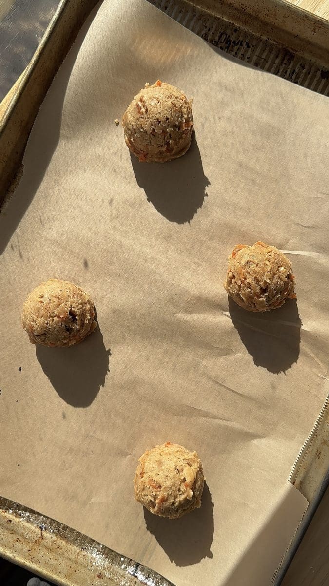 Cookie dough balls spaced out on a parchment lined baking tray.