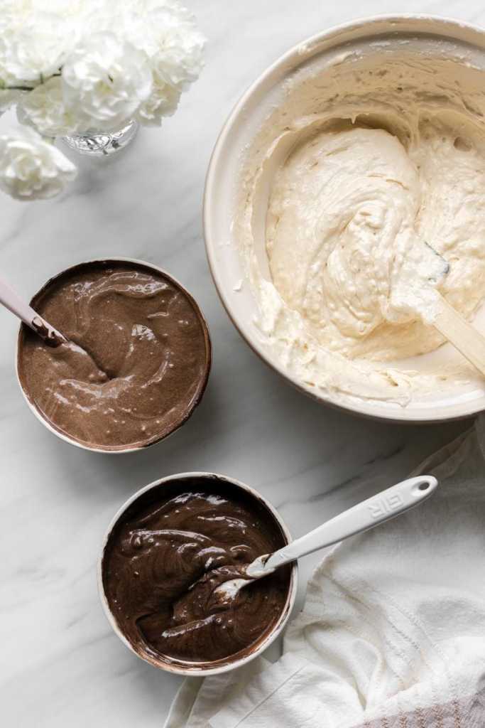 the bowl of vanilla cake batter next to two small bowls of the chocolate cake batter and espresso cake batter