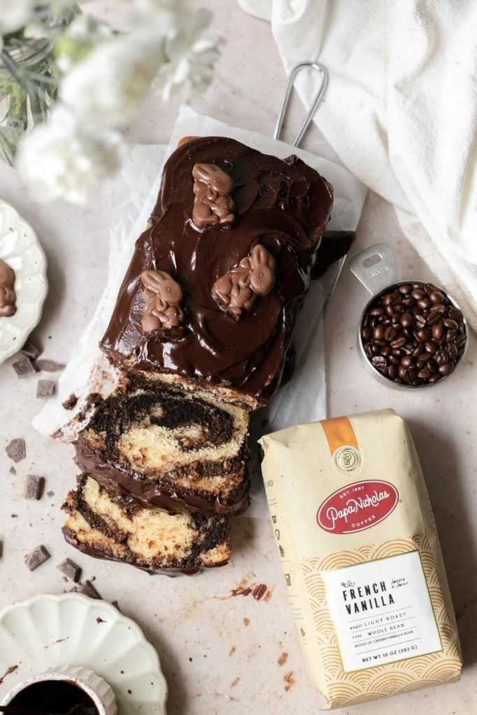 a flat lay of the loaf cake with two slices cut and laying down in front of it, next to a bag of papanicholas french vanilla espresso beans