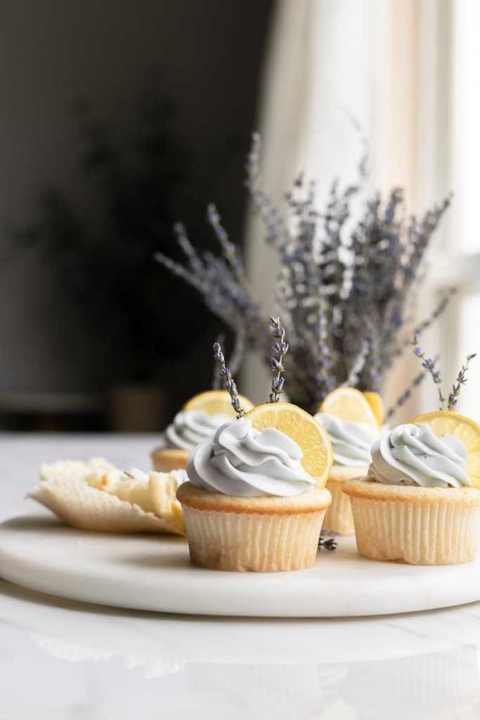 straight on view of the lemon lavender cupcakes with a vase of lavender behind them