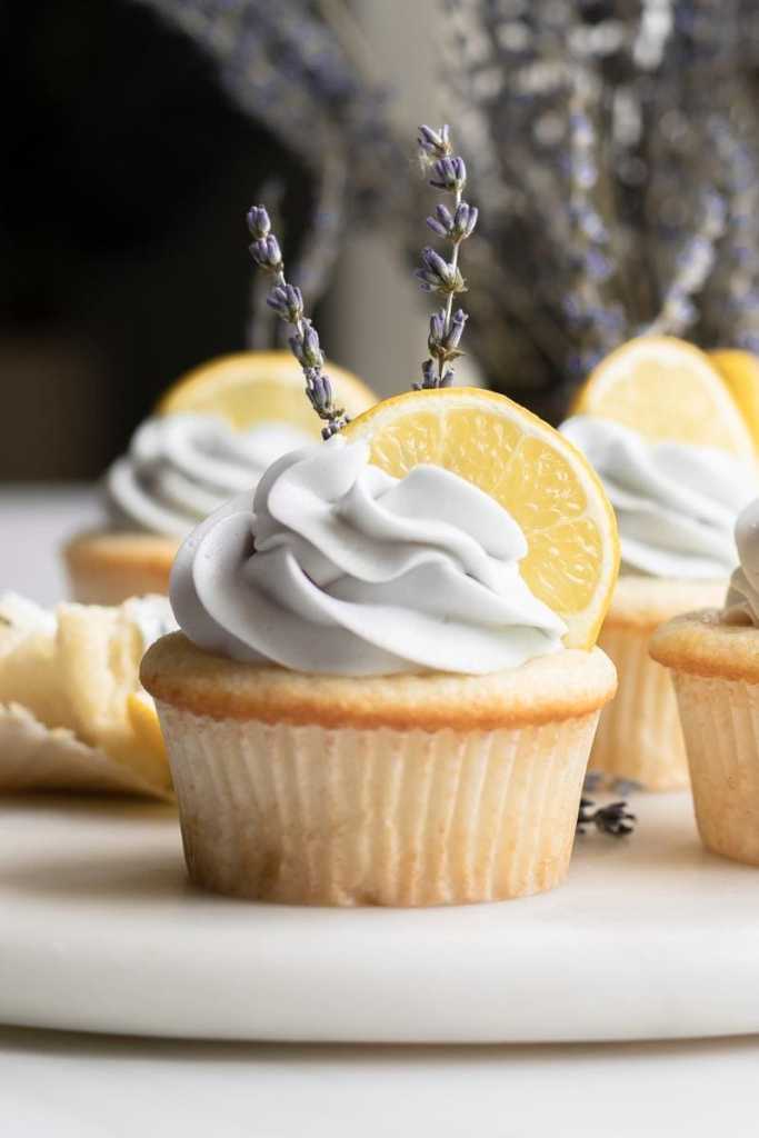 close up of the lemon lavender cupcake garnished with a lemon slice and two stems of lavender