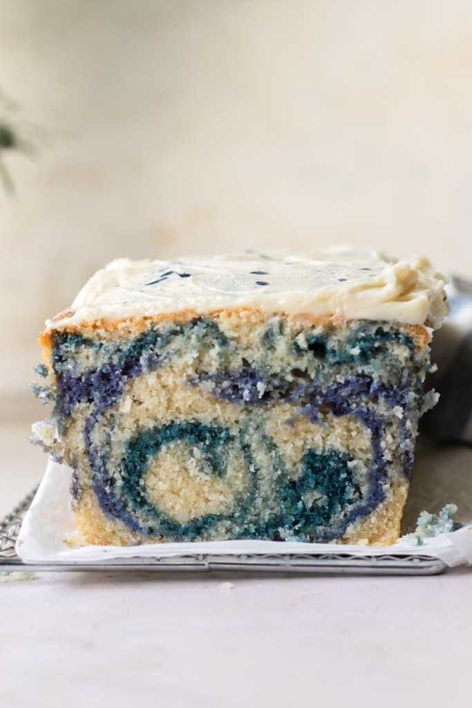A close up of the cross-section of the magic butterfly pea flower loaf cake, showing the vanilla, blue, and purple batters all swirled together.