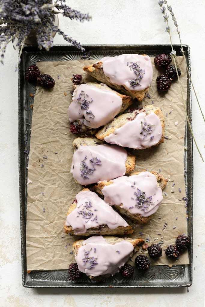 a flat lay of the blackberry lavender scones all laid in a straight line going up and down on a baking tray