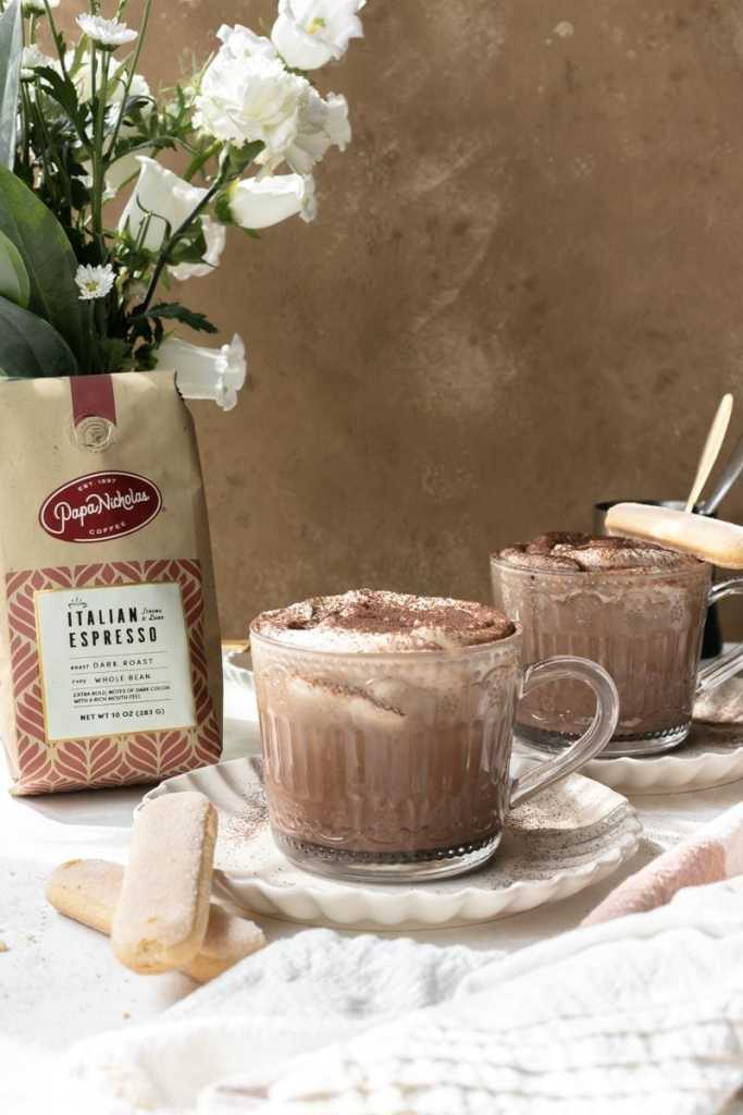 two tiramisu latte's staged next to a bag of Papanicholas Italian Espresso Beans