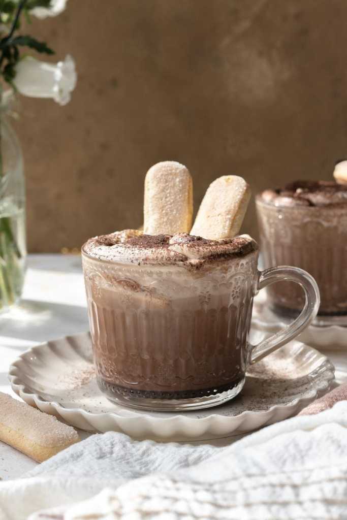 The tiramisu latte with two ladyfinger biscuits sitting inside of the drink, sticking out half way on the top.