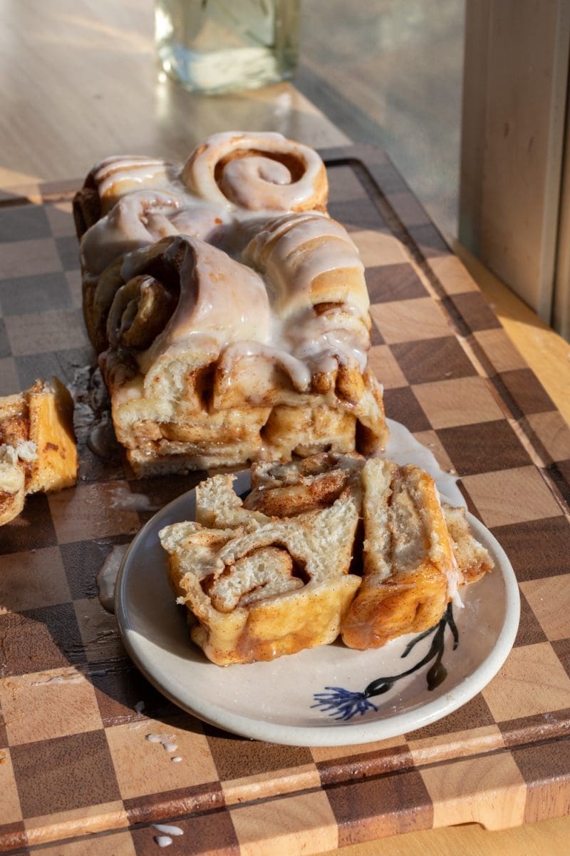 The whole cinnamon roll milk bread loaf with a slice in front of it.