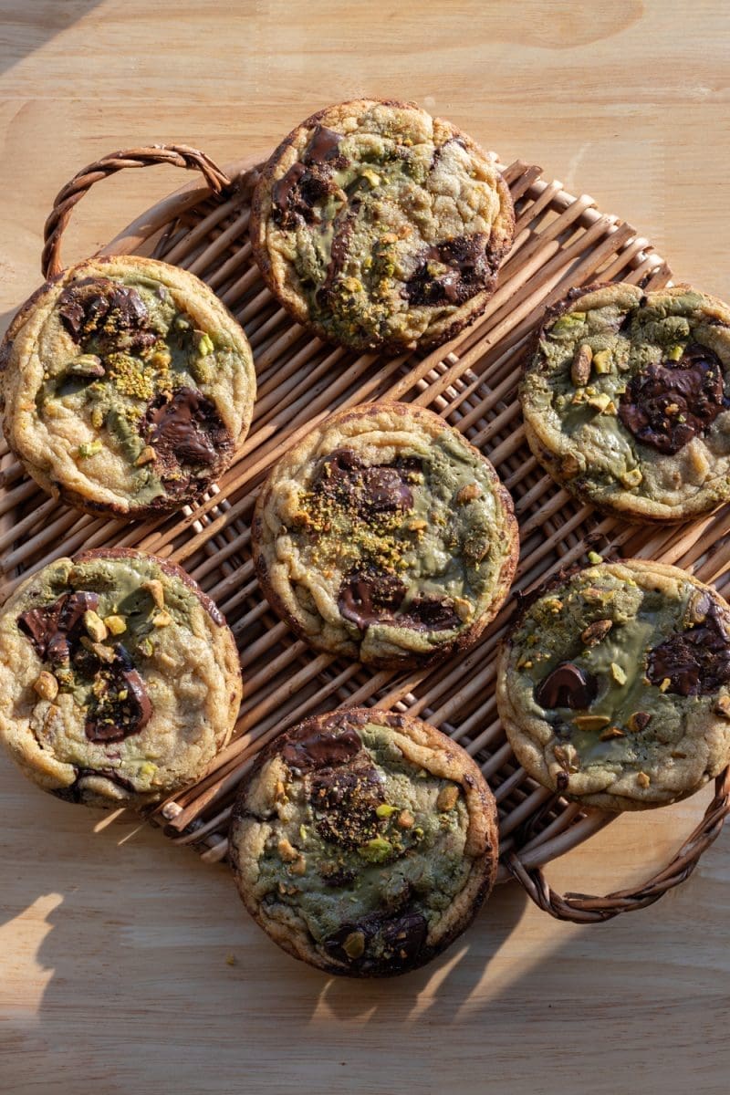 The pistachio cream chocolate chip cookies spread out on a tray.