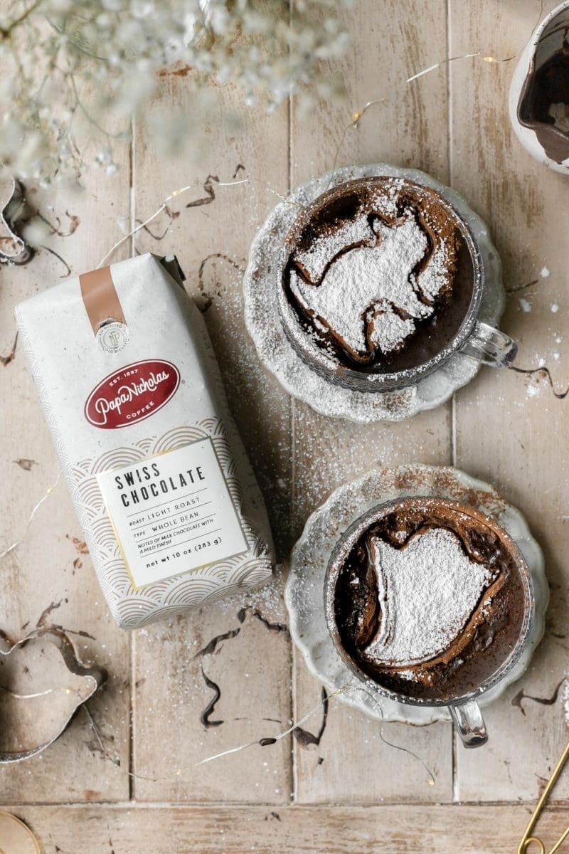 Two dark chocolate mochas next to a bag of coffee.