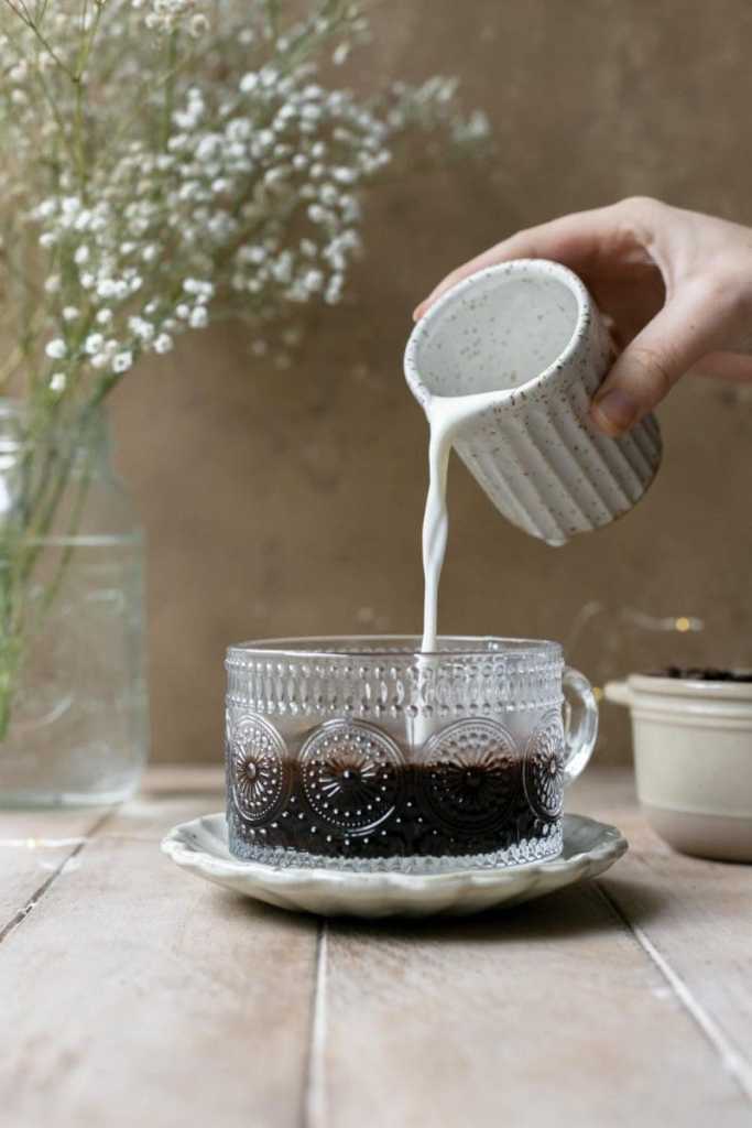 Pouring milk into the coffee cup.