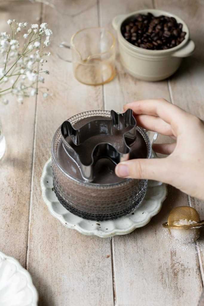 Holding a cat cookie cutter over the dark chocolate mocha.