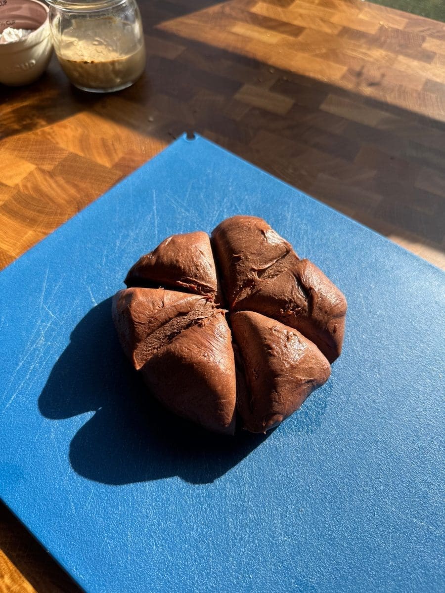 Chocolate brioche dough cut into six pieces on a cutting board.