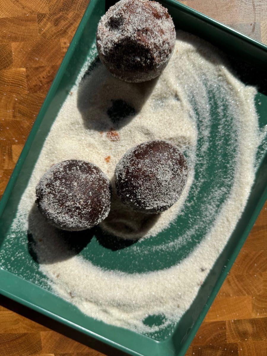 Coating the fried donuts with coffee sugar.