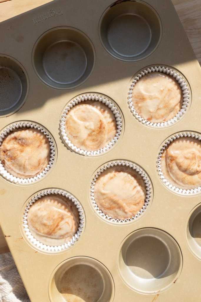 The cupcake batter distributed between parchment liners.
