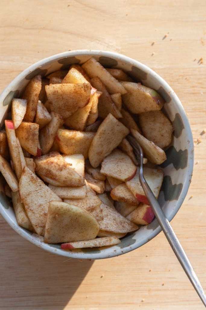 Sliced and spiced apples in a mixing bowl.