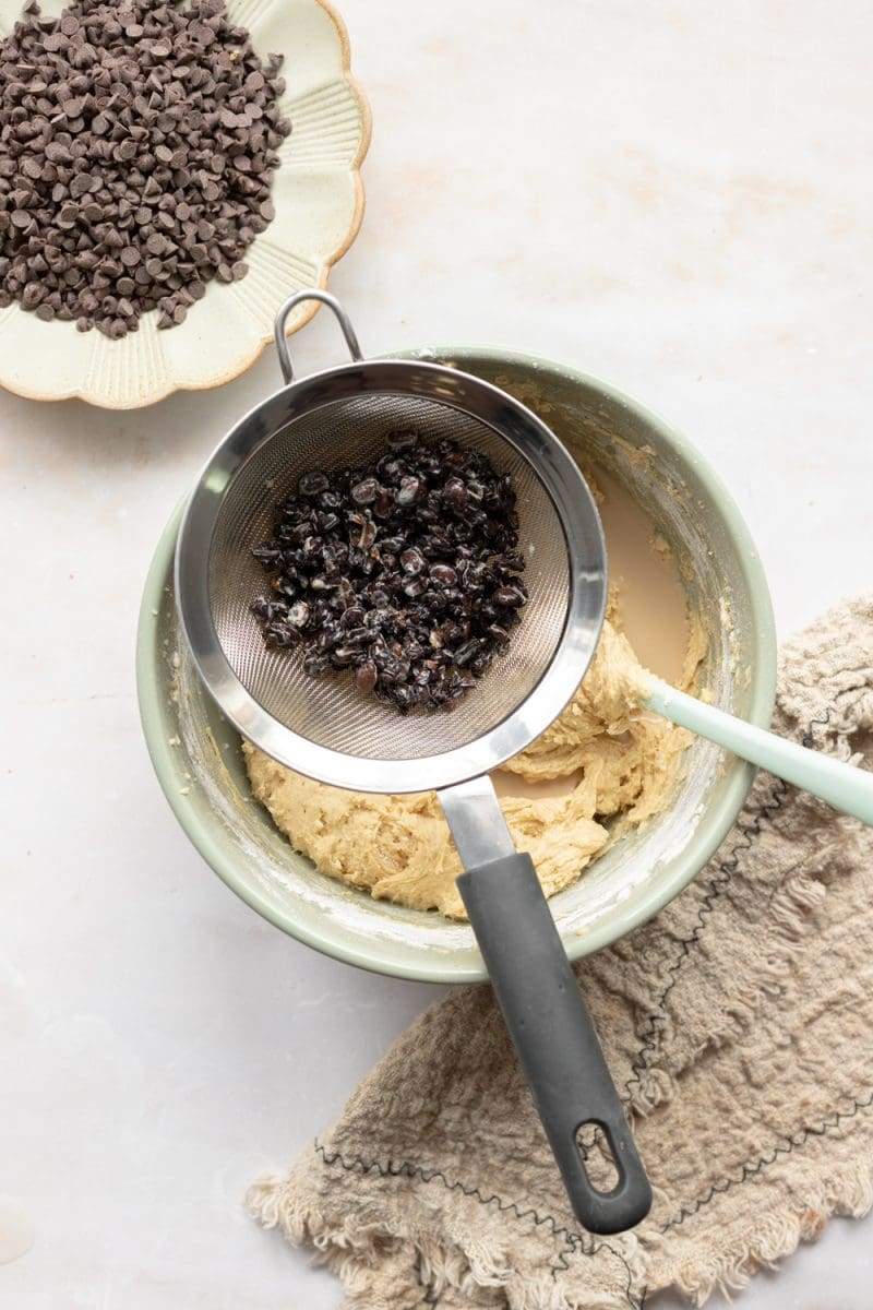 A fine mesh sieve over the mixing bowl with the espresso milk poured in.