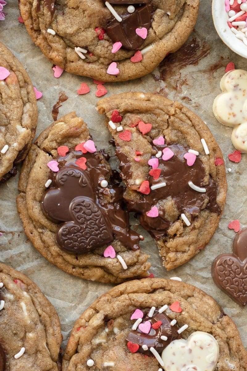 Close up of one of the valentine's day chocolate chip cookies which has been torn in half, with melted chocolate in the center.