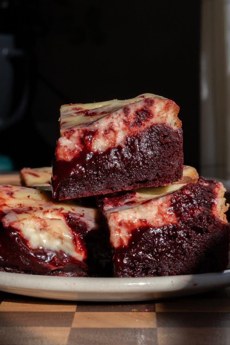 Small batch red velvet cheesecake brownies stacked on top of each other.