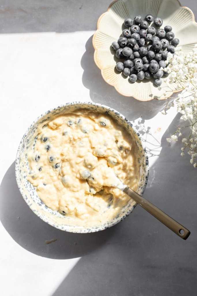 The blueberry muffin batter in a mixing bowl, prior to baking.