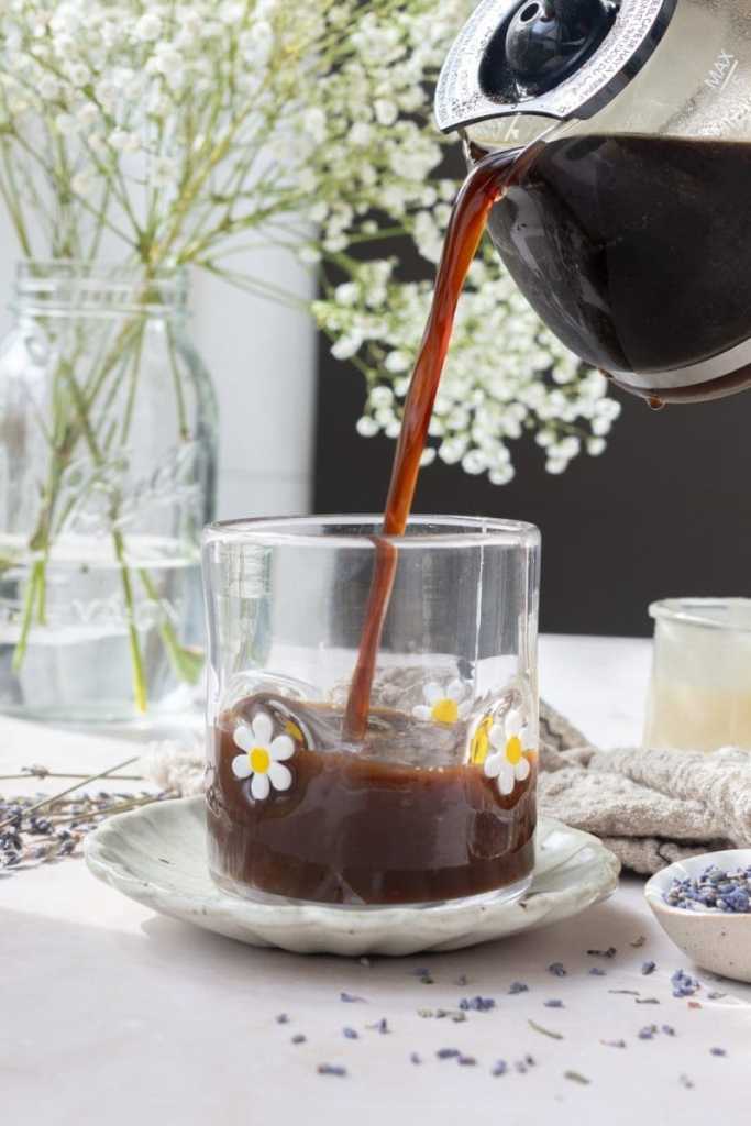 Pouring coffee from a coffee pitcher into the cup.