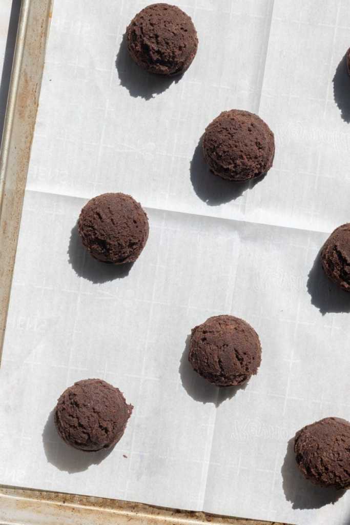 The cookie dough balls spread out on a cookie sheet.
