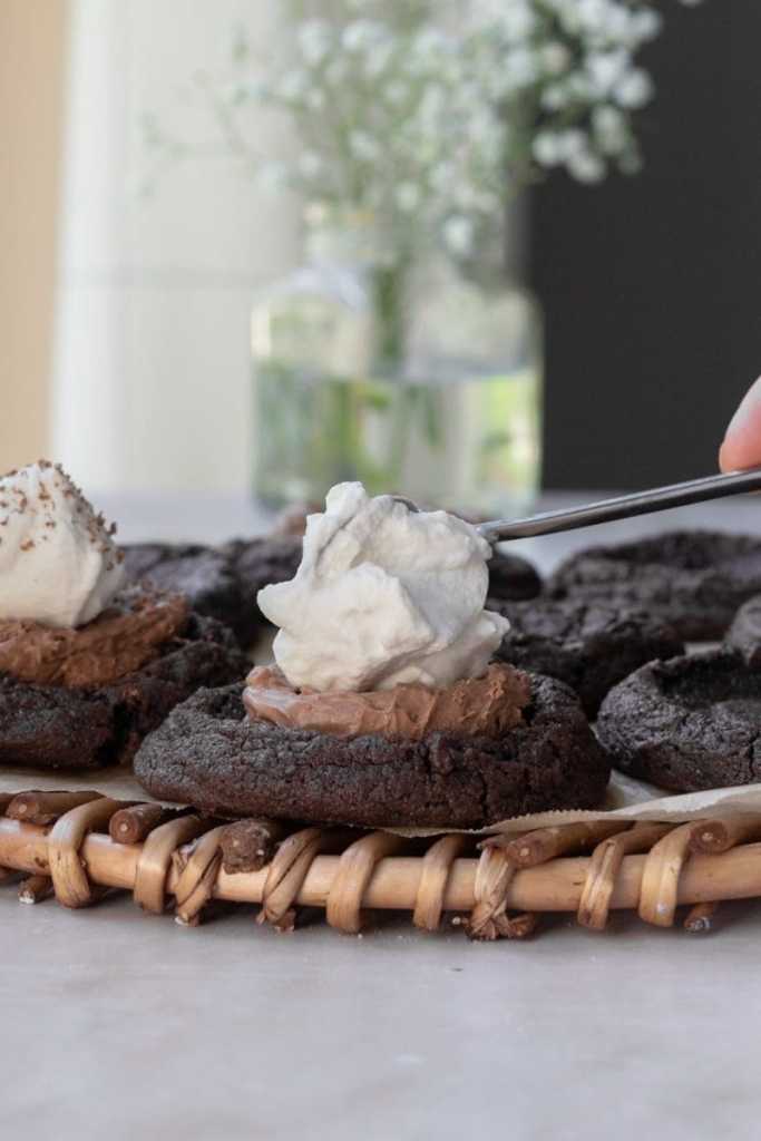 Putting whipped cream on top of the french silk pie cookies.