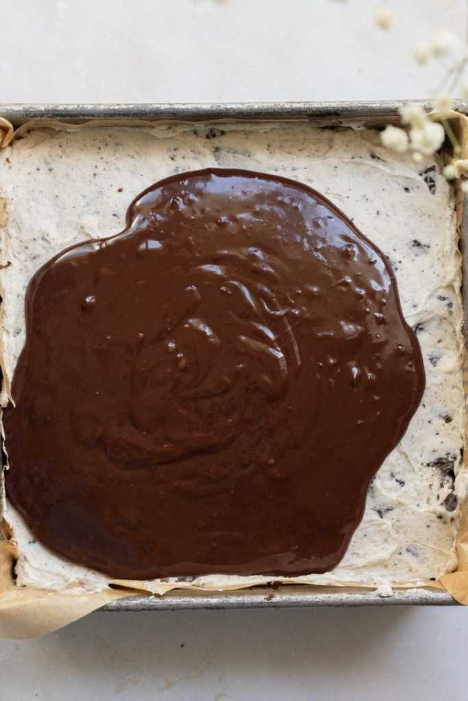 The ganache being spread over the buttercream on the brownies.