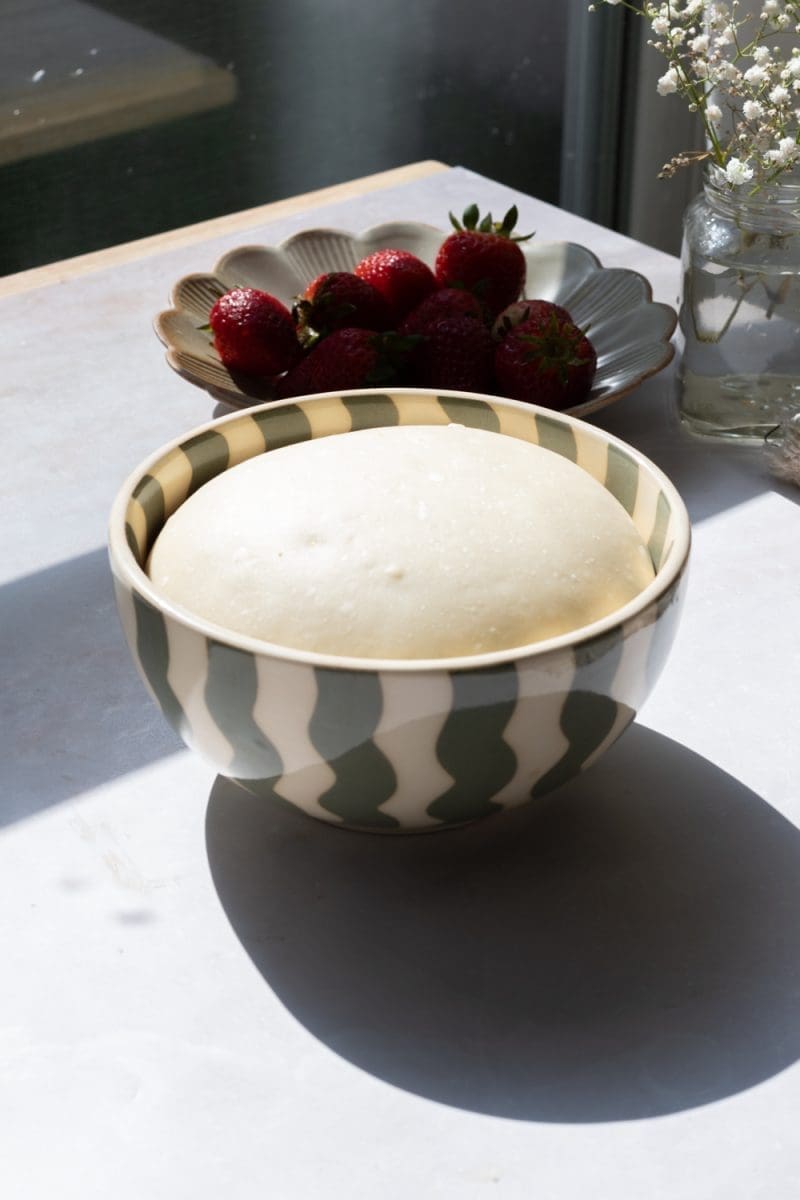 A mixing bowl with the risen milk bread dough in it.