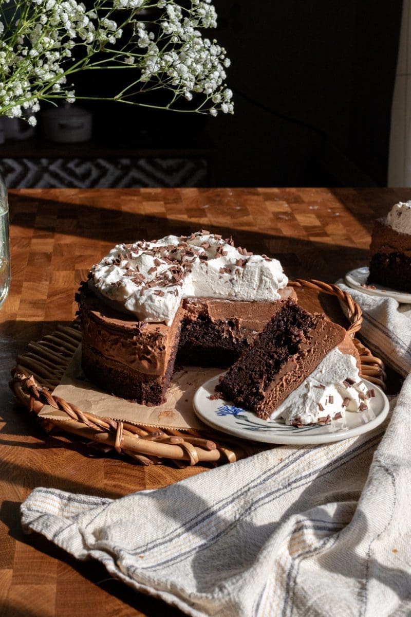 A slice of french silk chocolate cake in front of the whole cake.