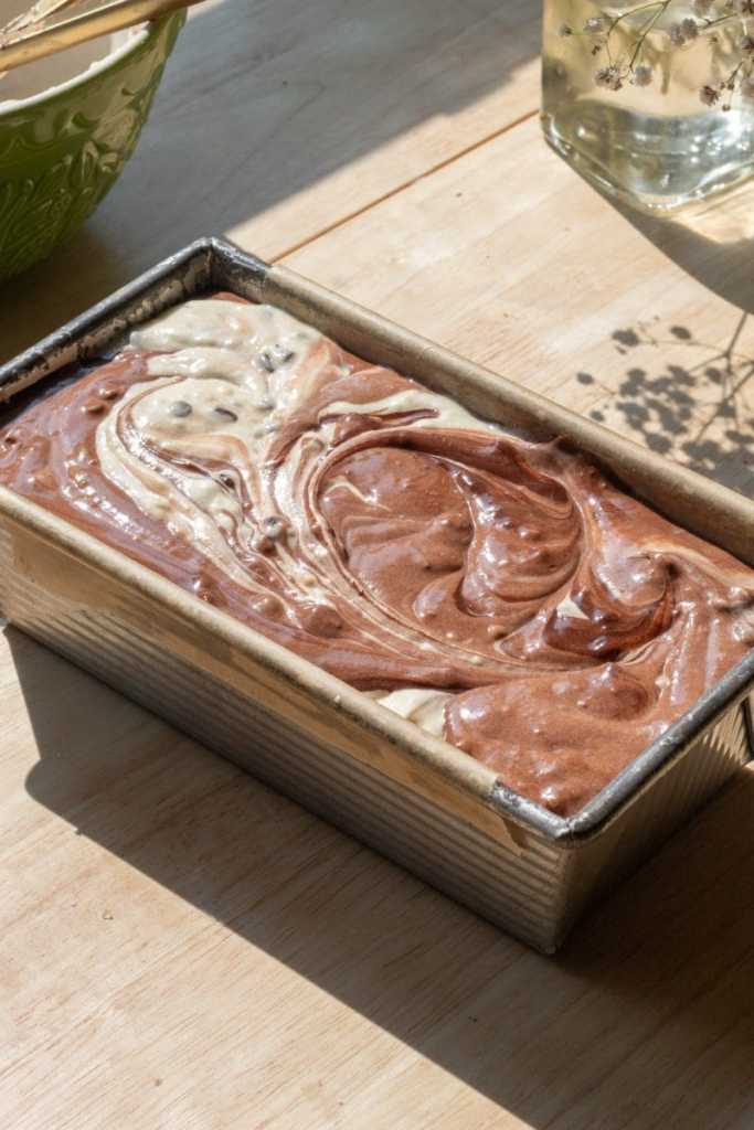 The cake in a loaf pan with the batters swirled together, before baking.