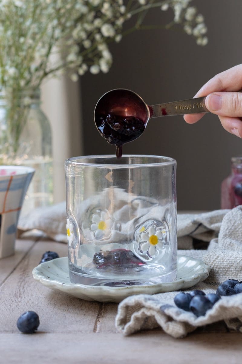 Pouring blueberry syrup into the cup.