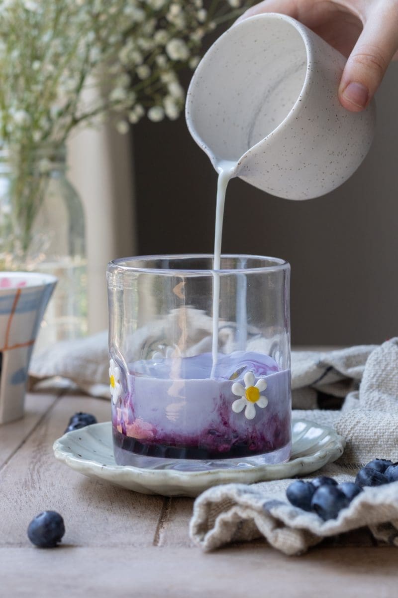 Pouring milk into the cup.
