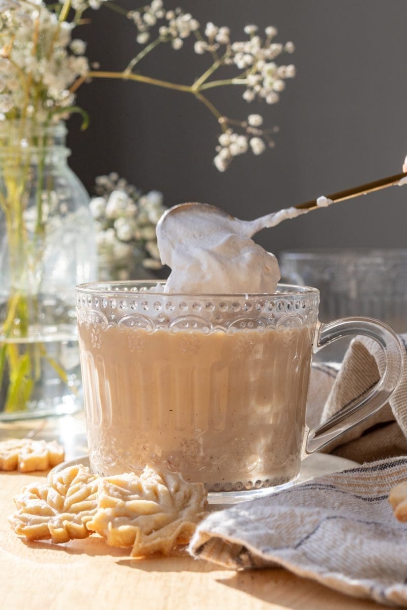 Placing whipped cream on top of the latte.