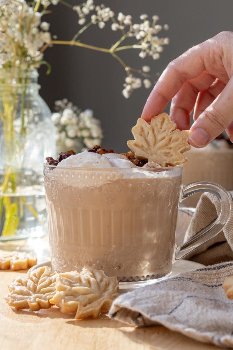 Placing a maple leaf cookie on top of the latte.
