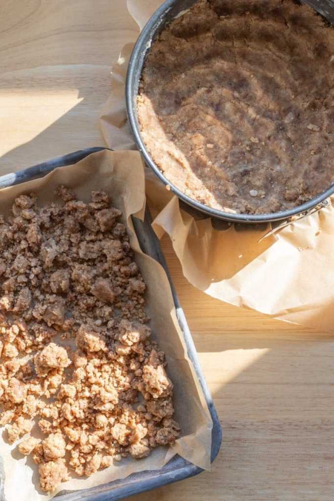 Shortbread crumbles on a baking tray and pressed into a springform pan.