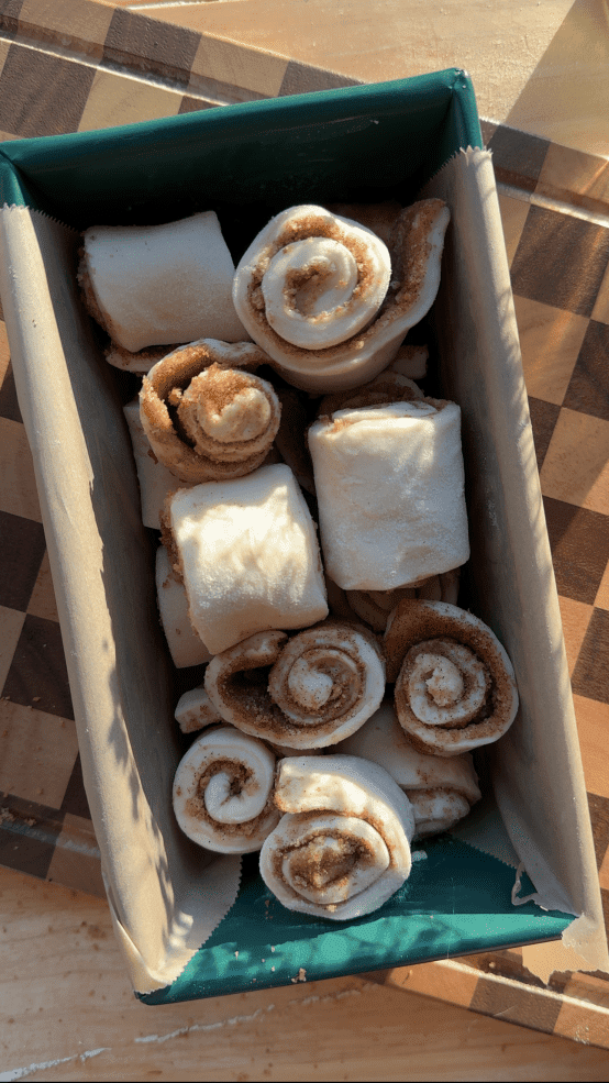 The cinnamon rolls layered up in a loaf pan.