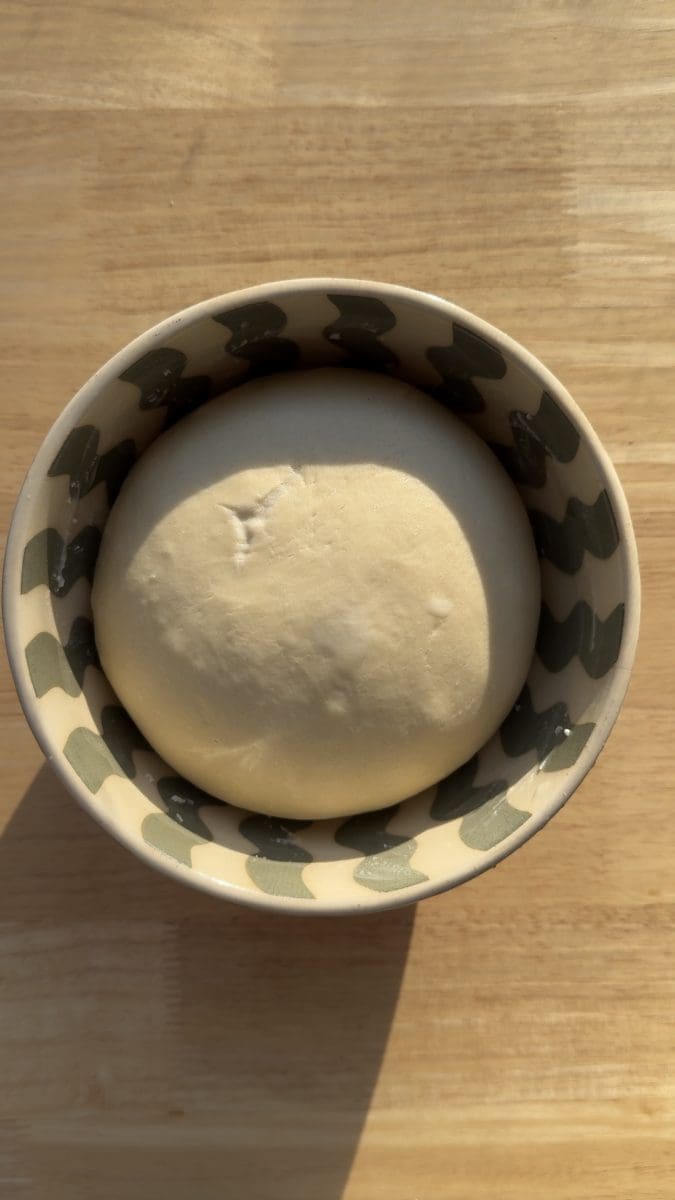 The risen dough in a small bowl.
