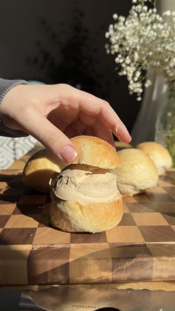 Topping the bun with the other half after filling it with cream.
