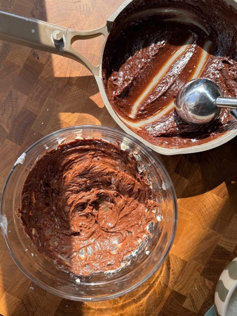 The saucepan with the chocolate egg mixture next to a bowl of the butter and chocolate beaten together.