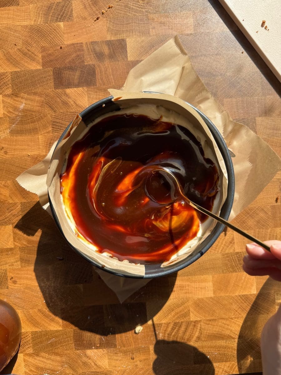 Spreading caramel sauce over the cake in the springform pan.