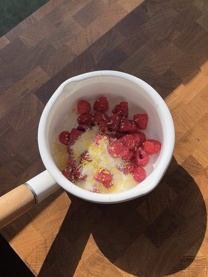 Raspberries, sugar, and lemon zest in a saucepan.